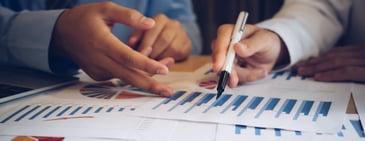Two professionals reviewing charts and bar graphs together, representing agencies aligning strategy and performance to drive profitability.
