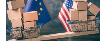 European Union and U.S. flags behind a seesaw balancing shopping baskets filled with cardboard boxes, symbolizing trade tariffs and market strategy