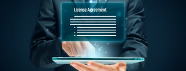 Businessman holding a digital tablet with a glowing holographic license agreement displayed above it