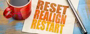 Coffee cup beside a napkin reading reset, realign, restart, symbolizing an Amazon KPI reset and renewed growth strategy.